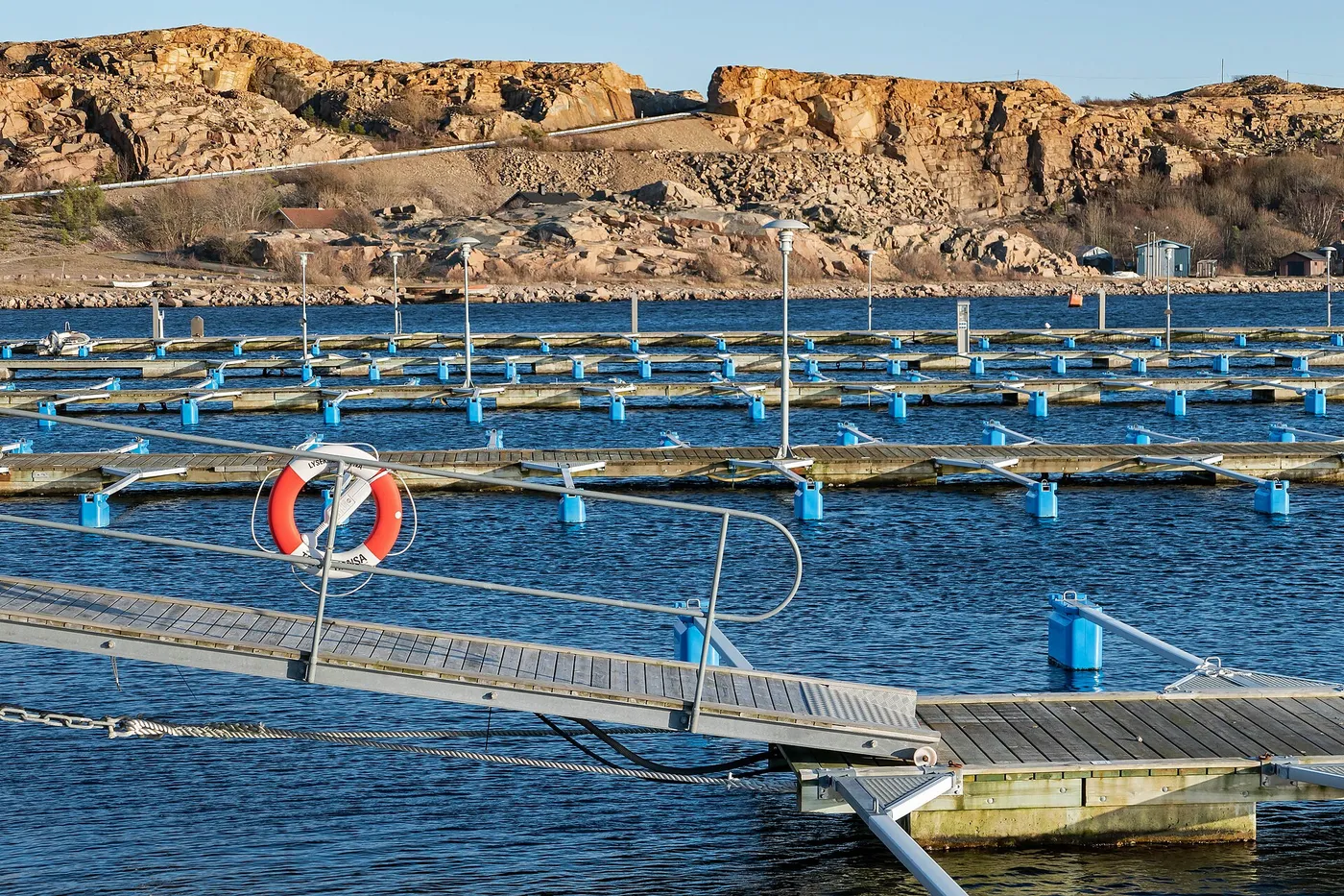 Aluminum marina gangway with handrails descending to a floating pontoon dock